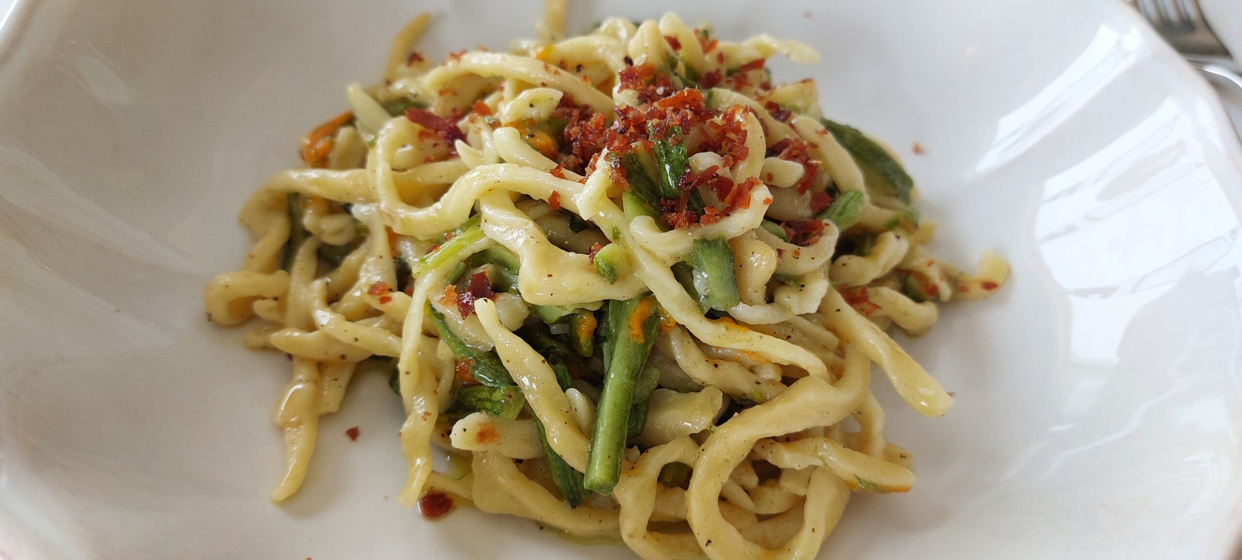 Strozzapreti con zucchine, loro fiori, e prosciutto croccante, articolo: Chef Laura Marciani, libertà, geniale, lussuria gustativa 2024, foto di Carol Agostini